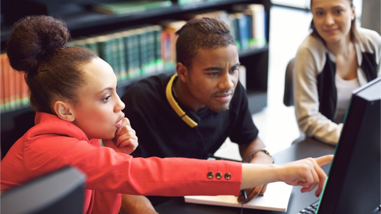 Woman showing a man something on a computer screen.