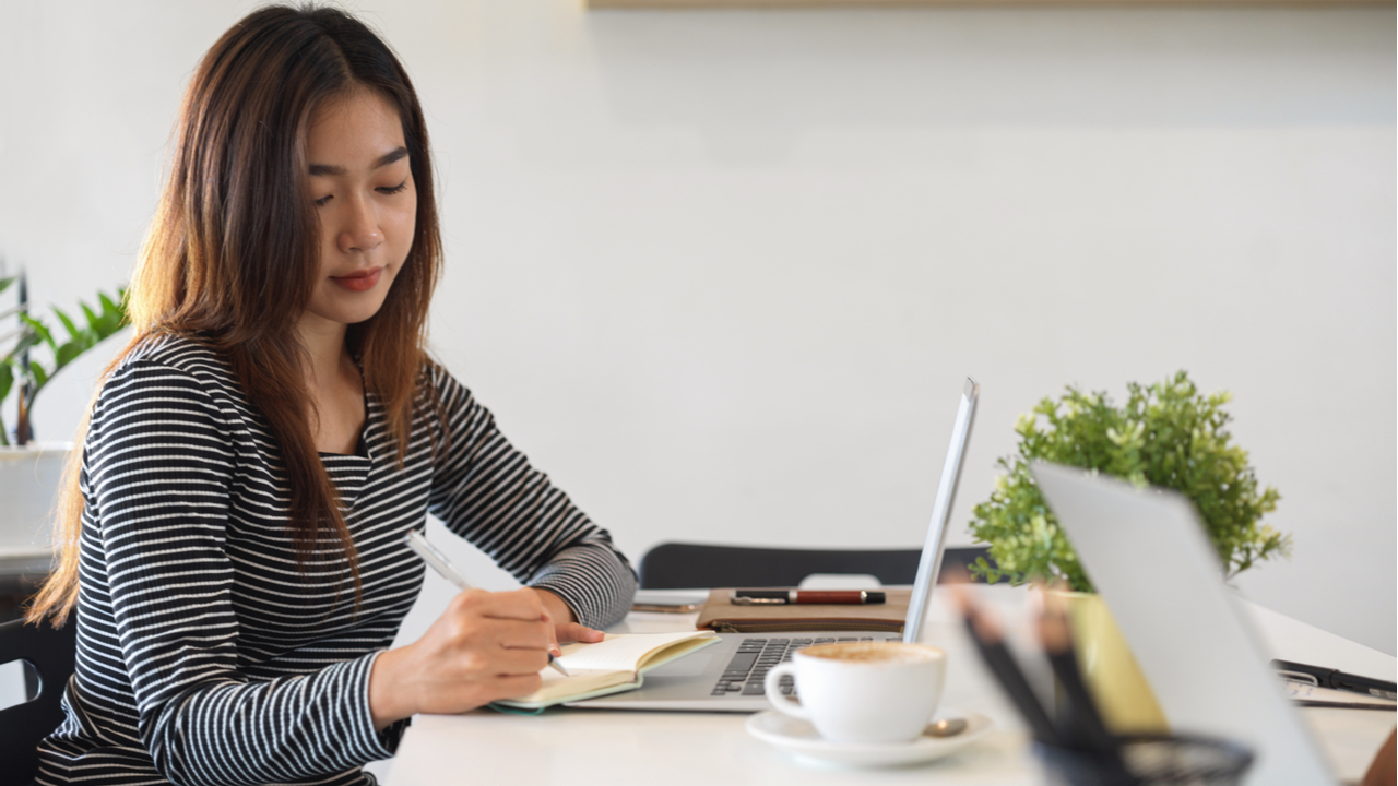 Women working at laptop with notebook and coffee