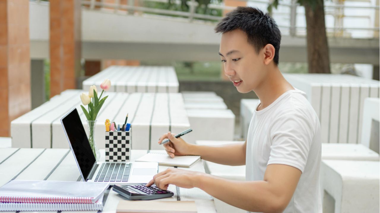 College student with calculator studying outdoors. 