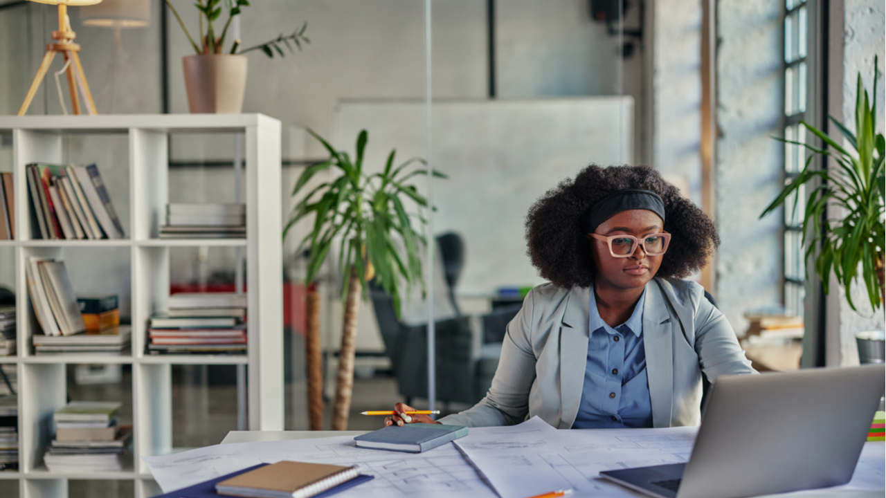 Black woman working in a loft with a laptop 